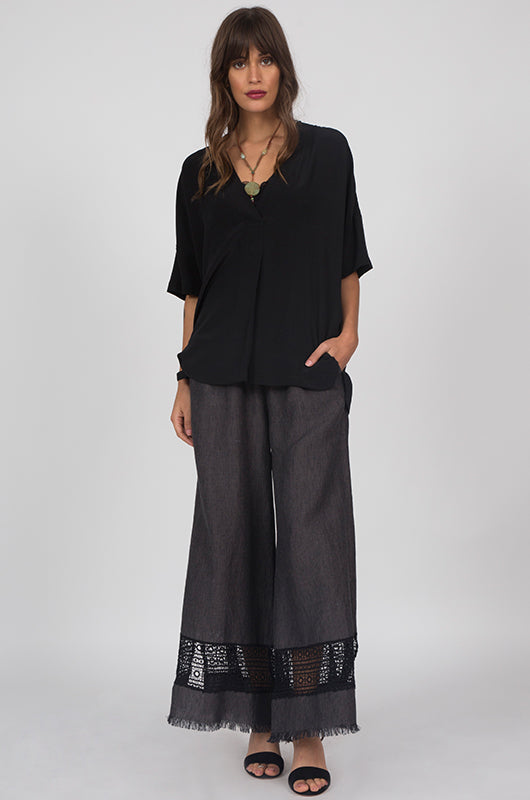 Model is wearing the Capri Lace Linen Pants in black with a black v neck wrap tee and open toe, ankle strap high heels.