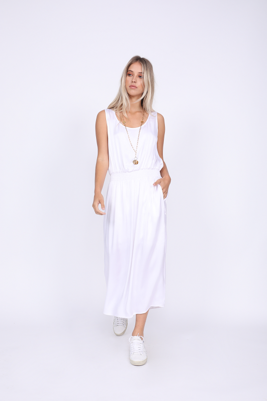 Model is wearing the Hayley Tank Dress in bright white with white sneakers (no socks) and a gold colored, long necklace.