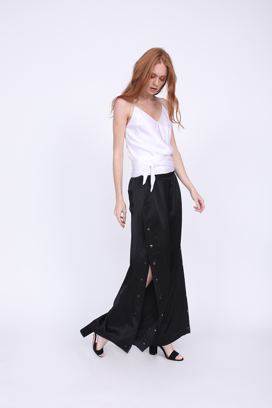 Model is wearing the Aimee Camisole in bright white, with sash tied around the waist. Worn with Hayley Wide Leg Snap Pant in black and black high heels.