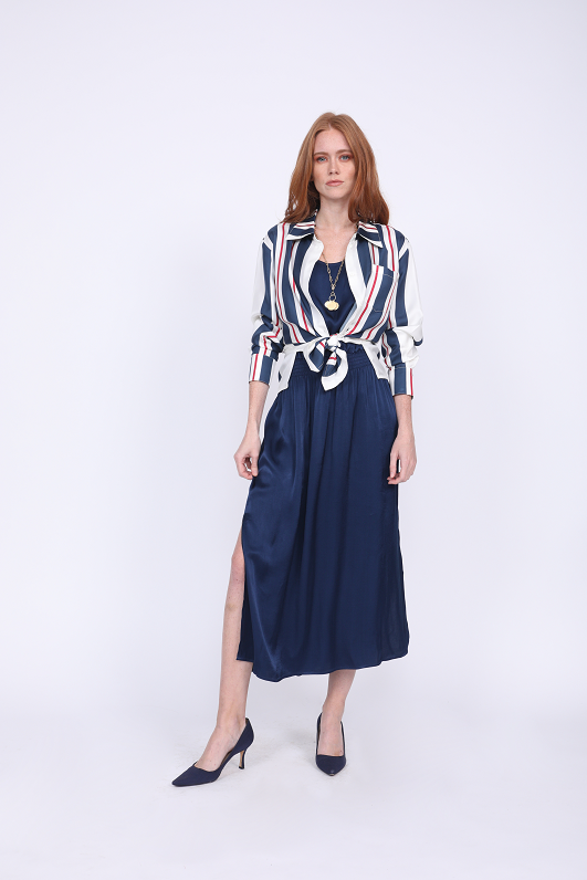 Model is wearing the Hayley Tank Dress in navy with the Bold Stripe Shirt in navy, worn unbuttoned and tied at the front waist, sleeves cuffed. Also worn with blue suede, pointed toe, kitten heels.