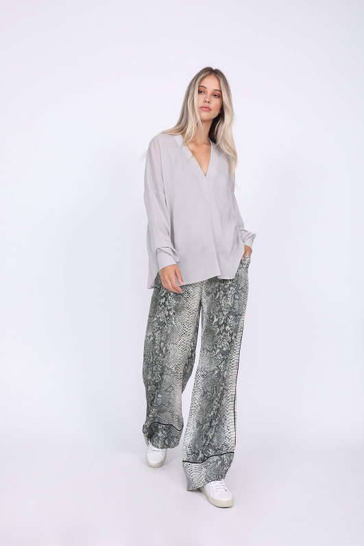 Model is wearing the Python Silk Print Wide Leg Pants in grey python with the Stretch Long Sleeve Tee in ice grey. Worn with white sneakers.