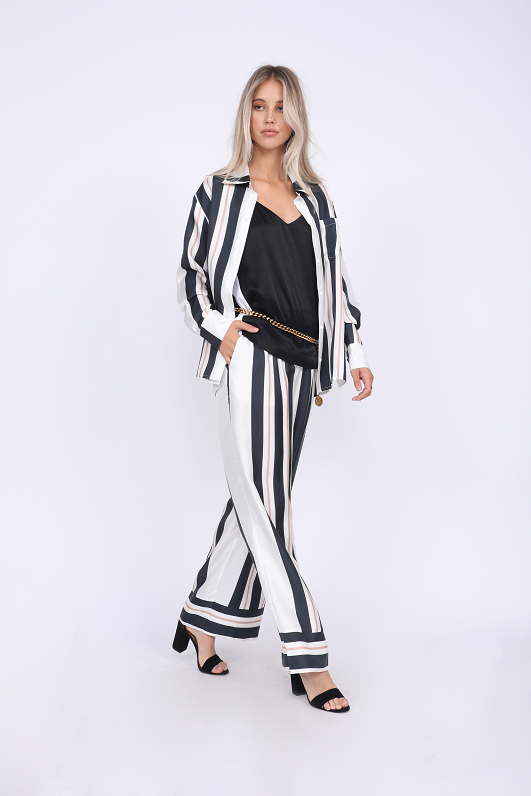 Model is wearing the Hayley Camisole in black, belted at the waist with a gold chain. Also worn with the Bold Stripe Pant in black, the Bold Stripe Shirt in black, and open toe, ankle strap, black high heels.