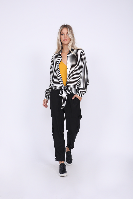 Model is wearing the Mini Stripe Shirt in black, unbuttoned and tied at front waist, with the Double Silk Solid Cami in gold underneath, tucked in, and the Tencel Cargo Pant in black. Also worn with black sneakers.
